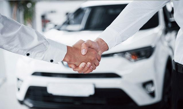 Acuerdo entre dos personas frente a un automóvil